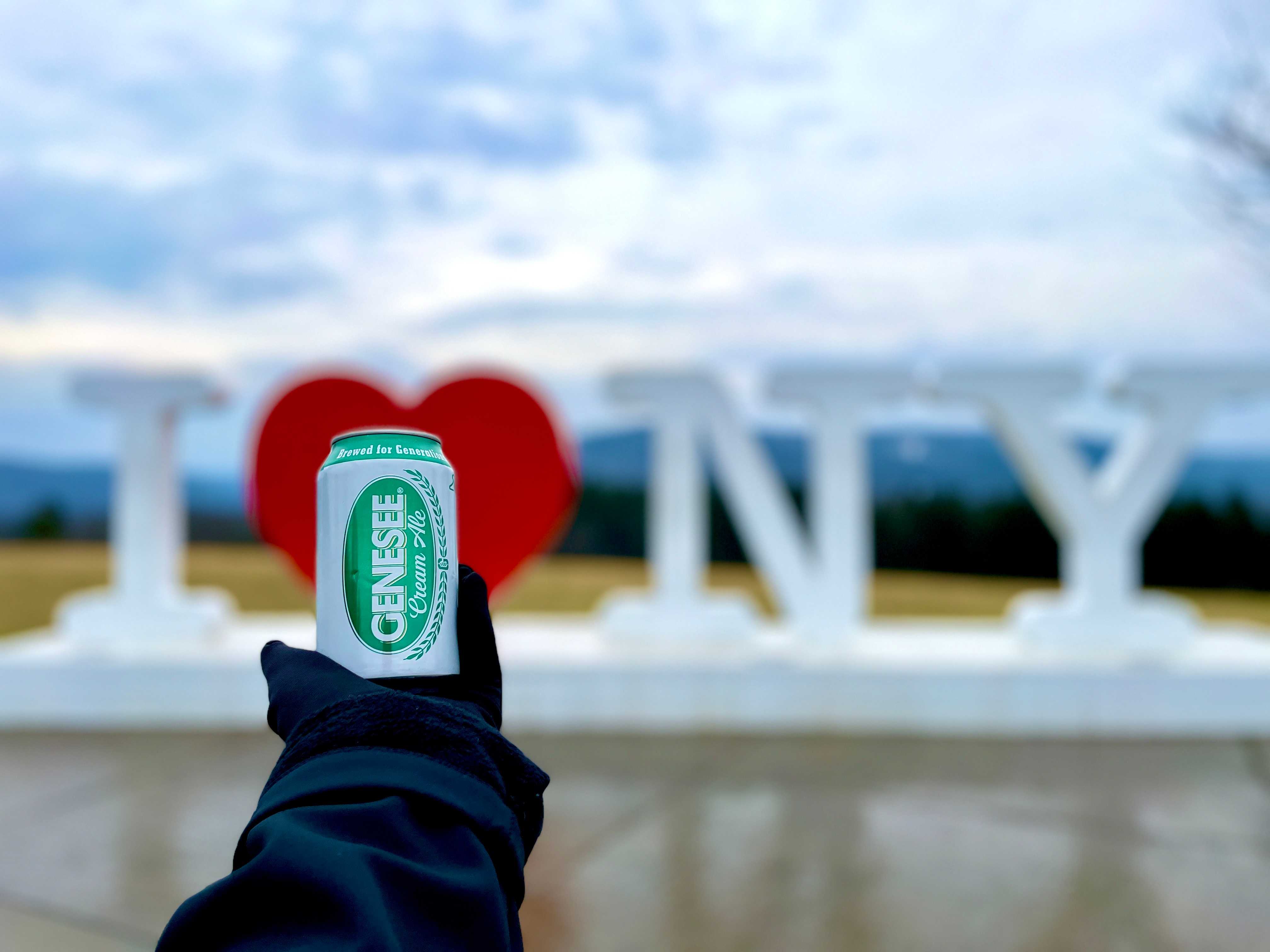 A can of Genesee Cream Ale in front of an I Love New York sculpture