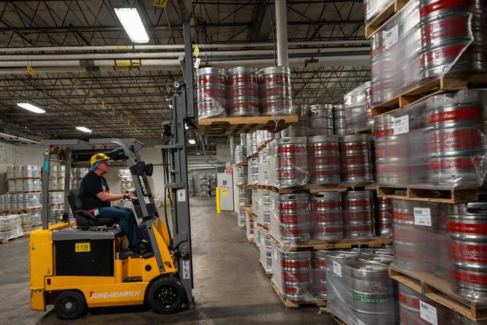 Photo of an operator driving a forktruck, stacking pallets of kegs