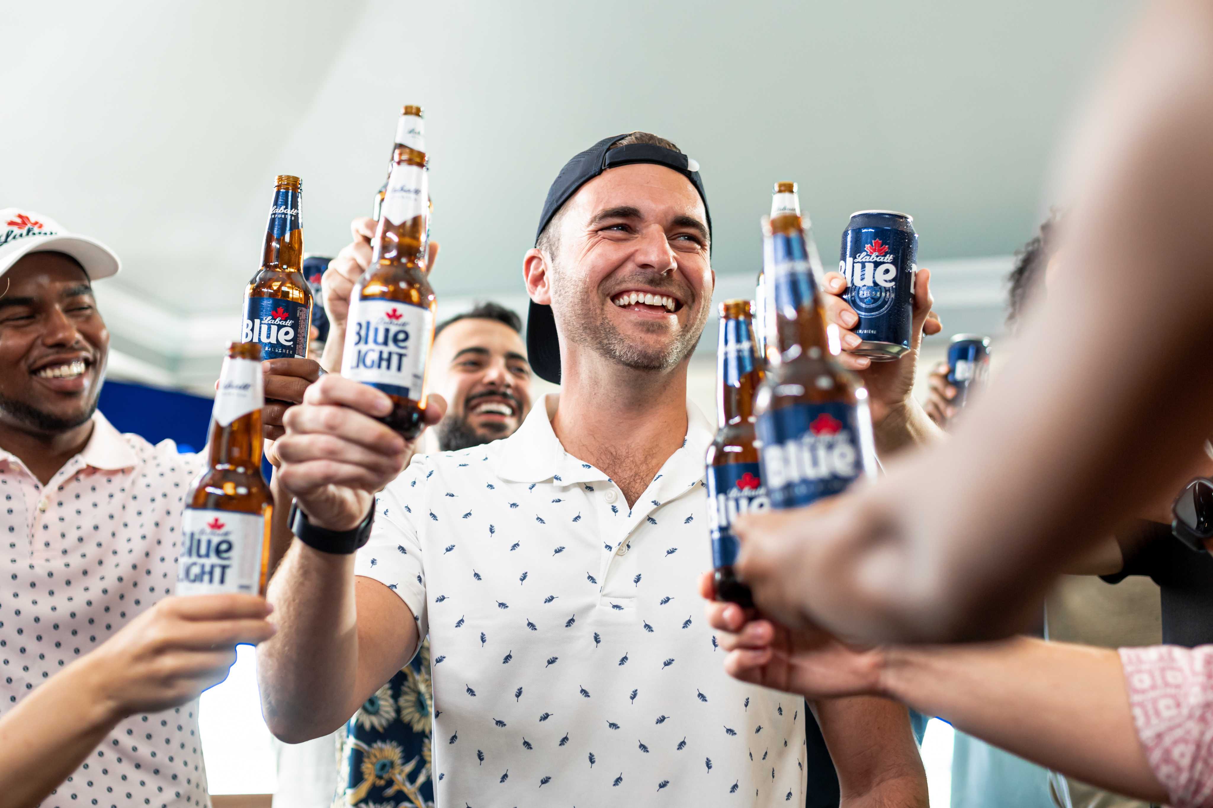 A group of people giving cheers with Labatt Blue and Blue Light bottles